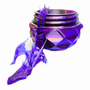 May include: A purple dragon-themed container with a geometric design. The dragon is intricately detailed, with a long neck and wings. The container has a threaded top and a faceted lower section. The color shifts between purple, blue, and gold.