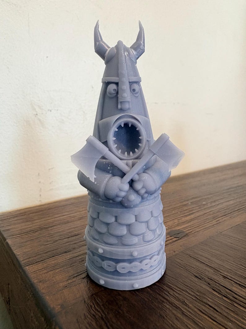 Op de afbeelding: Een lichtpaars 3D-geprint beeldje van een Vikingkrijger met een gehoornde helm. Het personage heeft een wijd open mond met zichtbare tanden en houdt twee gekruiste bijlen voor de borst. De basis is voorzien van een schubbenpatroon.