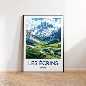 May include: A framed art print featuring a scenic mountain landscape with snow-capped peaks, a green valley, and three grazing sheep. The print has a blue sky with clouds and the text "LES ÉCRINS FRANCE" in navy blue.