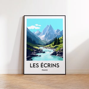 May include: A framed art print featuring a scenic landscape of the French Alps. The artwork depicts a river flowing through a valley with towering mountains, lush green hills, and a bright blue sky. The text "LES ÉCRINS FRANCE" is printed at the bottom.