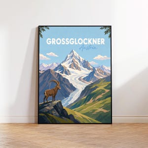 以下が含まれることがあります： オーストリアのグロースグロックナー山を描いた額入りトラベルポスター。イラストには、手前の岩場に立つ茶色のアイベックスと、背景に広がる雪を頂いた山頂と氷河、そして水色の空が描かれています。