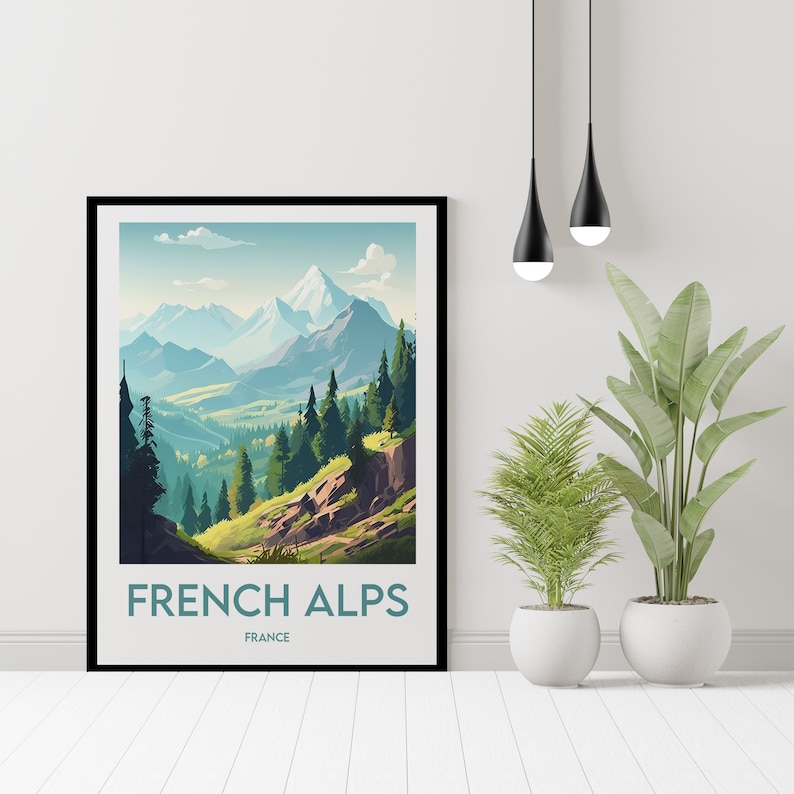 May include: A framed art print featuring a landscape of the French Alps. The artwork depicts a mountain range with snow-capped peaks, green valleys, and evergreen trees. The text "FRENCH ALPS FRANCE" is printed at the bottom of the frame.