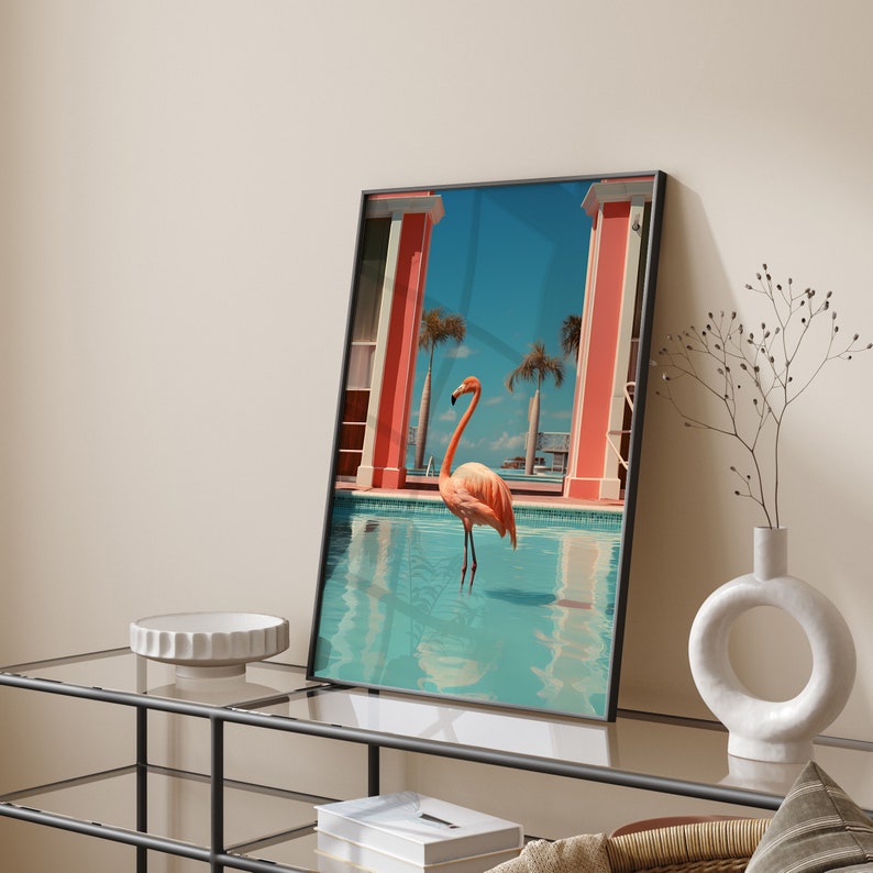 May include: A framed print of a pink flamingo standing in a blue pool with a pink and white building in the background.