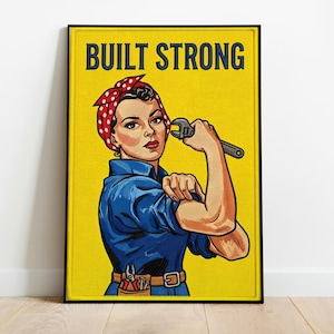 May include: A rectangular poster with a yellow background featuring the text BUILT STRONG in blue. The illustration depicts a person wearing a blue shirt and a red polka-dot headscarf, flexing an arm while holding a metal wrench in one hand.