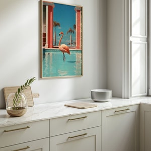 May include: A framed print of a pink flamingo standing in a blue pool with a pink building in the background.
