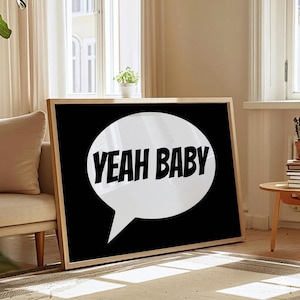 Könnte beinhalten: Gerahmter Kunstdruck mit dem Schriftzug "YEAH BABY" in fetten, schwarzen Buchstaben in einer weißen Sprechblase vor schwarzem Hintergrund. Das Kunstwerk wird in einem Raum mit natürlichem Licht und neutraler Farbpalette ausgestellt.