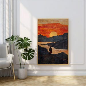 Könnte beinhalten: Ein gerahmter Landschaftskunst-Druck zeigt eine Figur mit einem Stab an einem felsigen Ufer, silhouettenhaft vor einem Sonnenuntergang. Der Himmel geht von Orange zu Gelb über, mit dunklen Bergen und Wasser im Hintergrund. Das Kunstwerk ist in einem goldenen Rahmen.