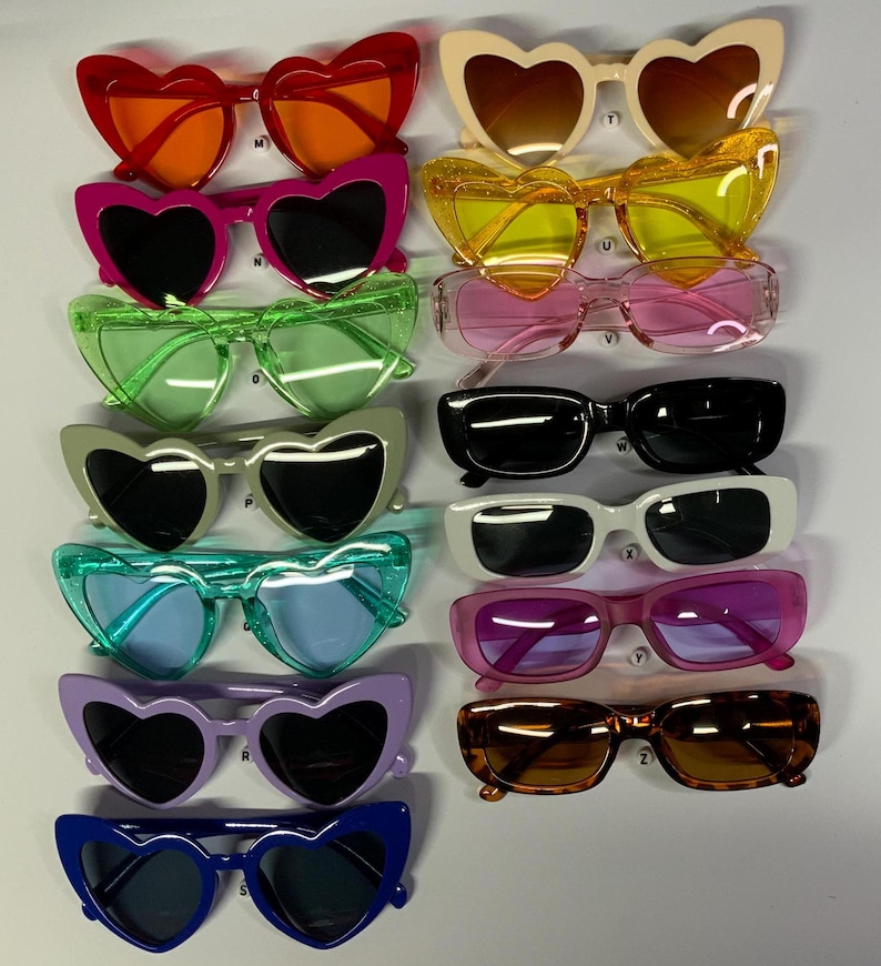 May include: A set of 12 pairs of heart-shaped sunglasses in various colors, including red, orange, pink, yellow, green, blue, purple, and black. The sunglasses have a retro style and are perfect for adding a touch of fun to any outfit.