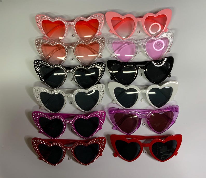 May include: A set of ten heart-shaped sunglasses with rhinestone accents. The sunglasses come in a variety of colors, including pink, red, black, white, and purple.
