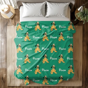 May include: A green blanket featuring a repeating pattern of the Disney character Pluto in a sitting pose. The word "Pluto" is written in a cursive font between each Pluto image. The blanket is on a bed with white pillows.