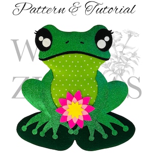 May include: A green frog with black eyes and a pink flower sits on a green lily pad. The frog is covered in glitter and the lily pad has a scalloped edge. The text "NO SEW" is written in pink letters below the frog.
