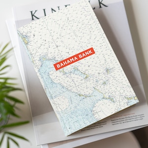 May include: A notebook with a nautical map design featuring the Bahamas. The cover has a red rectangle with the text "BAHAMA BANK" printed in white.