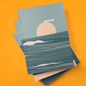 May include: A stack of notebooks with a teal cover featuring a minimalist design of a sun over ocean waves. The word "sawyer" is printed in white. The notebooks are on a bright orange background.