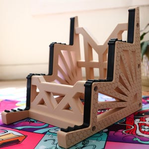 K&ouml;nnte beinhalten: Ein beigefarbener Kunststoff-Ablage-Regal mit schwarzen Akzenten. Das Regal hat ein geometrisches Design und besteht aus mehreren Ebenen.