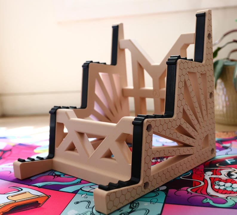 K&ouml;nnte beinhalten: Ein beigefarbener Kunststoff-Ablage-Regal mit schwarzen Akzenten. Das Regal hat ein geometrisches Design und besteht aus mehreren Ebenen.