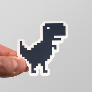 Könnte beinhalten: Ein schwarzer und weißer pixelartiger Dinosaurier-Aufkleber. Der Dinosaurier blickt nach rechts und hat ein kleines Auge.