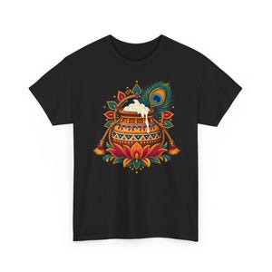 May include: A black t-shirt featuring a central graphic of a brown clay pot filled with white cream, resting on a colorful lotus flower. The design includes a peacock feather, decorative tassels, and intricate geometric patterns in red, blue, and gold.