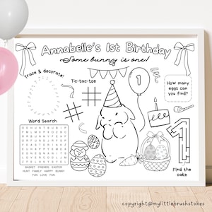 Puede incluir: Una hoja de actividades imprimible en blanco y negro para la fiesta de cumpleaños de un niño. La hoja presenta un conejo con un sombrero de fiesta, un globo número uno, un pastel y una cesta de huevos. El texto "Annabelle's 1st Birthday Some bunny is one!" está en la parte superior de la hoja. También hay varios juegos y actividades para que los niños completen, como una búsqueda de palabras, un juego de tres en raya y una actividad de unir los puntos.