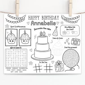May include: Black and white birthday activity placemat with the text "Happy Birthday Annabelle". Includes a word search, spot the difference, tic-tac-toe, and a maze. Features illustrations of cupcakes, a cake, and a gift.