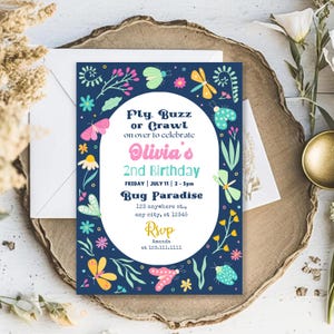 Könnte beinhalten: Eine blaue Einladung mit einem floralen Rand und bunten Insekten. Der Text lautet "Fly, Buzz or Crawl on over to celebrate Olivia's 2nd Birthday. Friday | July 11 | 2-5pm Bug Paradise 123 anywhere st., any city, st 12345 RSVP Amanda at 123.111.1111"