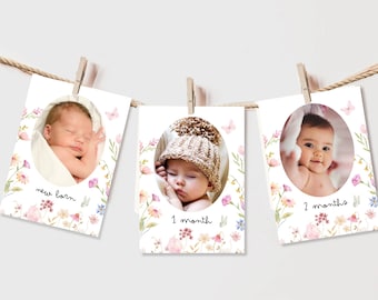 May include: Three white photo cards with a floral design and a baby in each photo. The cards are hung on a string with clothespins. The text on the cards reads "new born", "1 month", and "2 months".