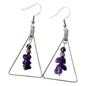 May include: A pair of handmade earrings featuring a silver triangle design. Each earring has a cluster of deep purple amethyst stones and silver beads suspended from a silver hook.