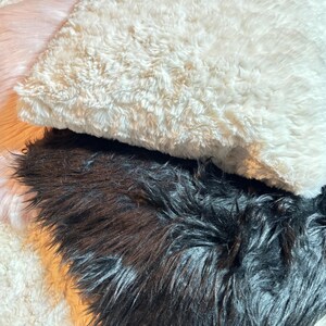 Könnte beinhalten: Drei Dekokissen aus Kunstfell in verschiedenen Farben: Weiß, Creme und Schwarz. Die Kissen sind weich und flauschig und eignen sich perfekt, um jedem Raum einen Hauch von Luxus zu verleihen.