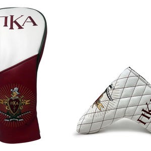 May include: Two golf club head covers. One is white and burgundy with "ΠKA" in burgundy and a crest. The other is white with a diamond pattern, "ΠKA" in burgundy, and a crest.
