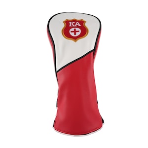 May include: A golf club headcover featuring a red and white color scheme with black piping. The top section is white, while the bottom is red. A shield-shaped emblem is centered at the top, displaying the letters KA above a red cross symbol.
