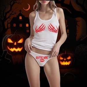 May include: A white tank top featuring red skeleton hand graphics on the chest and matching white bikini-style underwear with the red text BITE ME and a graphic of vampire fangs printed on the front center.