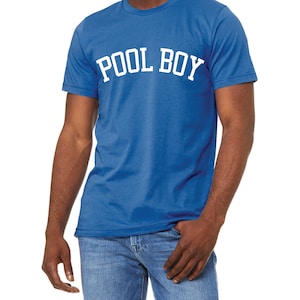 May include: A royal blue short-sleeve t-shirt featuring the text POOL BOY printed in a bold, white, arched collegiate-style font across the chest. The garment has a crew neckline and a standard fit, paired with blue denim jeans.