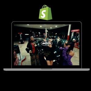 Può includere: Uno schermo di computer portatile che mostra una scena di quattro persone in piedi di fronte a una stazione di servizio di notte. Le persone indossano abiti casual e la scena è illuminata dalle luci della stazione di servizio. Il testo "ENTER THE NOWNESS" è visibile sullo schermo.