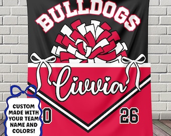 May include: A personalized red and black Bulldogs banner with the name "Livia" in white script. The banner features a pom-pom graphic and the numbers "0" and "26". The text "CUSTOM MADE WITH YOUR TEAM NAME AND COLORS!" is also included.