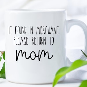 May include: White ceramic mug with black text that reads "If found in microwave please return to mom".