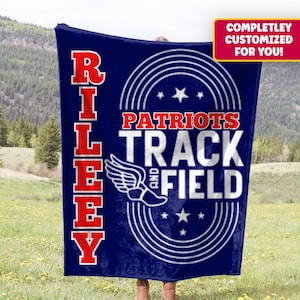 Op de afbeelding: Een marineblauwe deken met de naam "Riley" in rode blokletters aan de linkerkant. De deken heeft de woorden "Patriots Track and Field" in het wit, met een gevleugelde schoenafbeelding en sterren. Een rode banner leest "VOLLEDIG AANGEPAST VOOR U!"