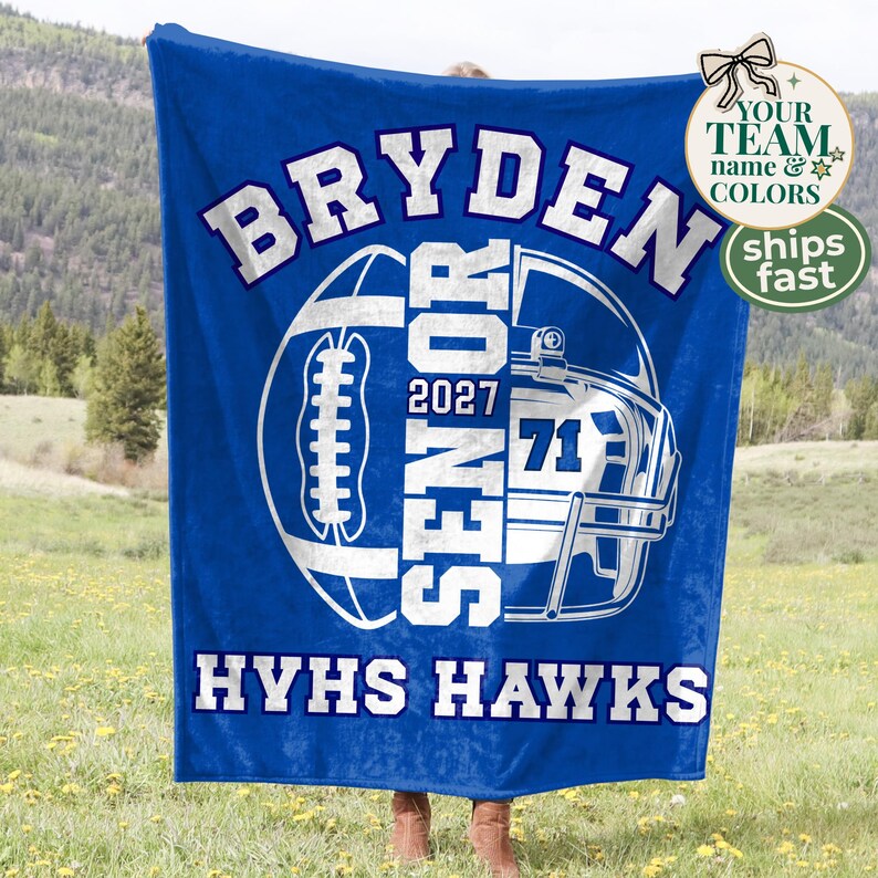 May include: A royal blue fleece blanket featuring a white graphic of a football helmet and a football. The text reads BRYDEN, SENIOR, 2027, 71, and HYHS HAWKS in bold white lettering. The design is centred on the fabric with a soft texture.