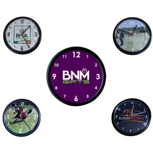 May include: Four black framed clocks with different designs. The first clock has a green, white, and black logo with the text "IIHA APPROVED". The second clock has a purple background with the text "BNM GIFTS" in white and green. The third clock has a picture of a horse jumping over a fence. The fourth clock has a picture of a car with the text "ELSIVER MODELS".