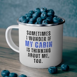 May include: White enamel camping mug with a blue and black graphic that says "Sometimes I wonder if my cabin is thinking about me, too."