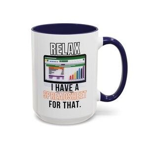 Op de afbeelding: Witte keramische koffiemok met een blauwe rand en handvat. De mok heeft een afbeelding van een spreadsheet met de tekst "Relax I have a spreadsheet for that."