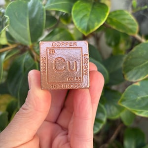 May include: A copper cube with the element symbol Cu, labelled "COPPER" at the top. The cube displays the atomic number 29, atomic mass, and other scientific data. It weighs 283 grams.