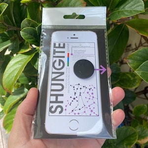 Puede incluir: Una agarradera de teléfono negra con fondo blanco y texto en ruso e inglés. El texto dice "Para los queridos de Carelia" y "Placa para teléfono móvil y todos los dispositivos electrónicos".