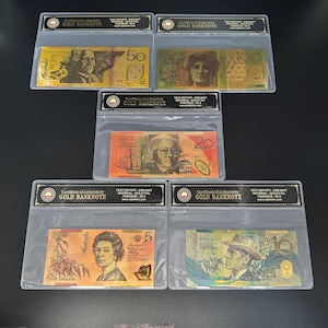 Op de afbeelding: Verschillende Australische gouden bankbiljetten in beschermende hoezen. De coupures zijn 5, 20, 50 en 100 dollar. Elke biljet toont portretten en gedetailleerde ontwerpen, met de tekst "Certificate of Authenticity GOLD BANKNOTE" op de hoezen.