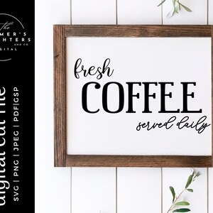 May include: A white sign with a brown wooden frame, featuring the text "fresh COFFEE served daily" in black cursive and block lettering.