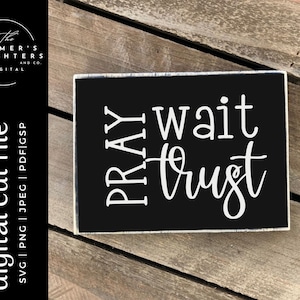 May include: A black wooden sign with white text that reads "PRAY wait trust".