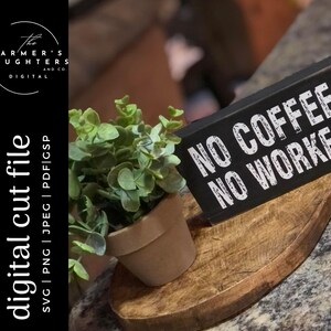 May include: A black wooden sign with white text that reads "NO COFFEE NO WORKEE" is displayed on a wooden chopping board with a small potted plant.