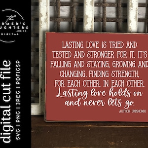 May include: A red wooden sign with white text that reads "Lasting love is tried and tested and stronger for it. It's falling and staying, growing and changing. Finding strength, for each other, in each other. Lasting love holds on and never lets go. Author Unknown."