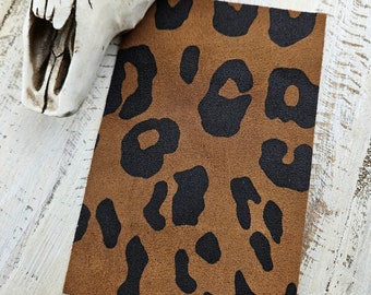 May include: A brown faux suede fabric with a black leopard print pattern.