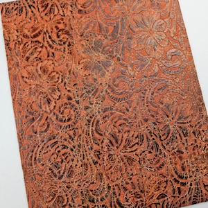 May include: A sheet of brown faux leather with an embossed floral pattern. The leather has a distressed look, with a slightly raised texture.