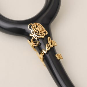 Peut inclure: Stéthoscope noir avec une rose dorée et le nom "Melly" gravé sur le côté.