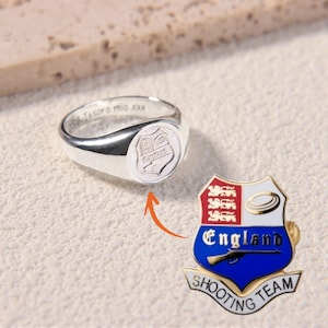 Può includere: Un anello con sigillo d'argento con uno stemma inciso e l'iscrizione "SSB Tesoro mio xxx". Accanto, una spilla con l'emblema dell'England Shooting Team, con un fucile e le parole "England Shooting Team".